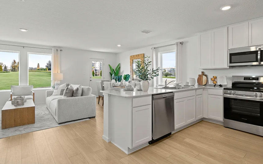 Kitchen with island and stainless-steel appliances opening to the living and dining areas