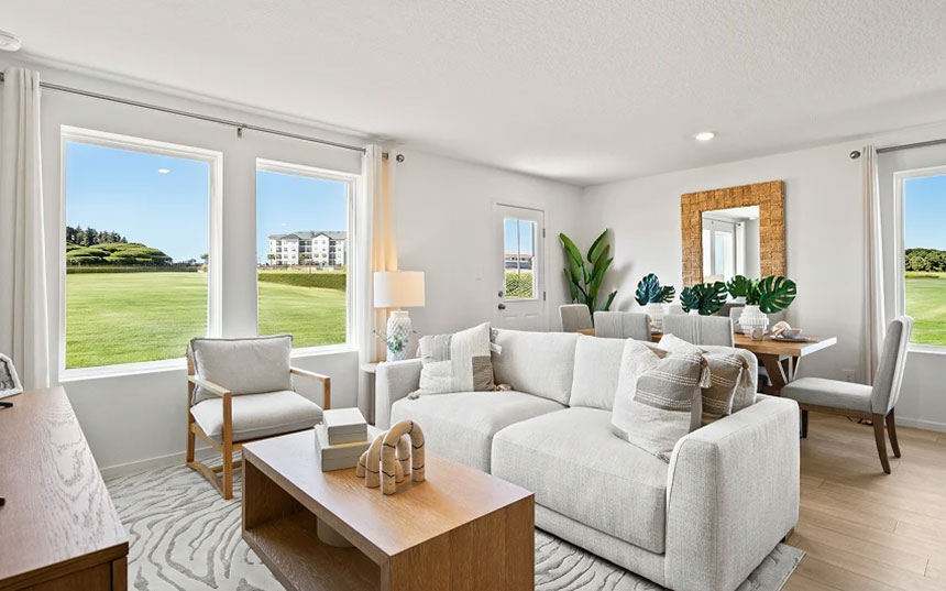 Bright furnished living room with large windows overlooking landscaped green space