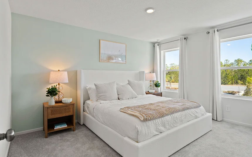 Primary bedroom with a neutral finish, carpeted floor, and two windows