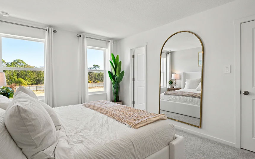 Primary bedroom showing its natural light, wall mirror, and adjoining doorway