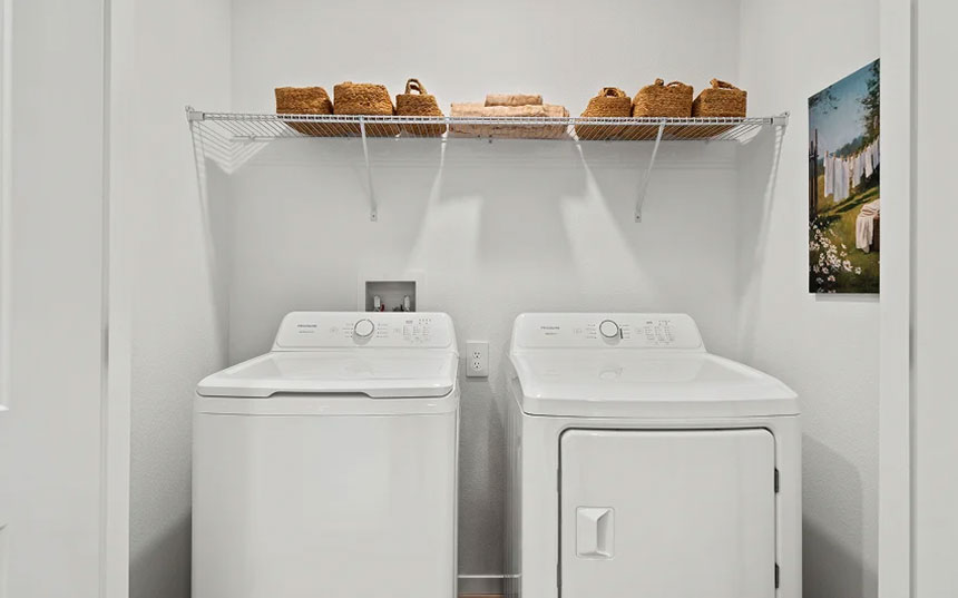 Dedicated laundry area with a full-size washer, dryer, and overhead storage shelf